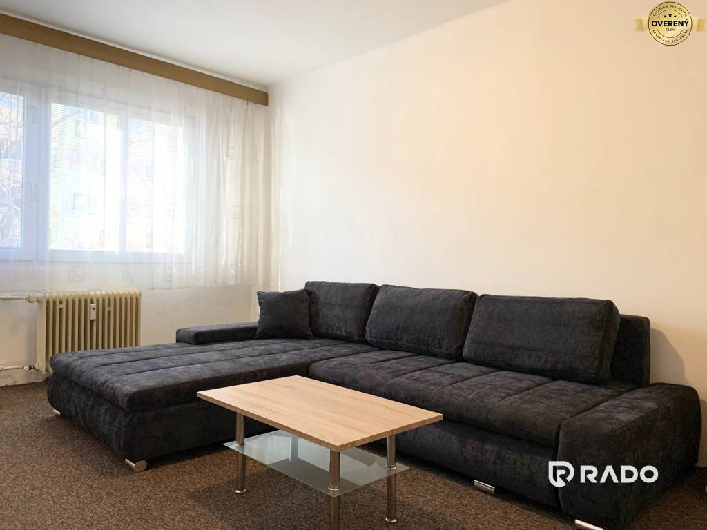 Obývacia izba v 2-izbovom byte s úplne novým veľkým gaučom a konferenčným stolíkom